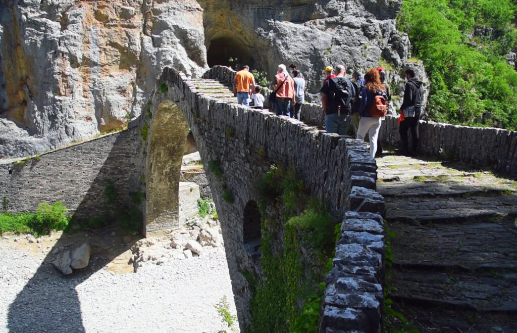 People crossing a stone bridge in Zagori